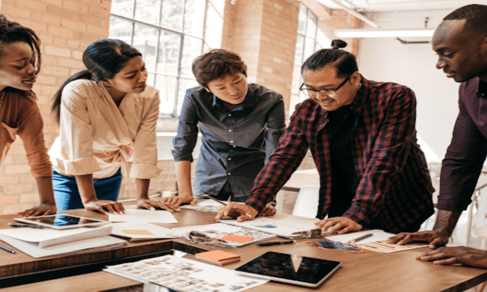 A diverse team of startup founders discussing business insurance documents and risk planning strategies in a modern office setting.