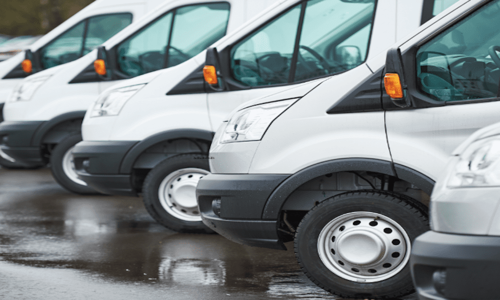 Fleet of white commercial vans parked in a row, symbolizing business auto coverage and the importance of insuring company vehicles to manage risk and reduce premiums.